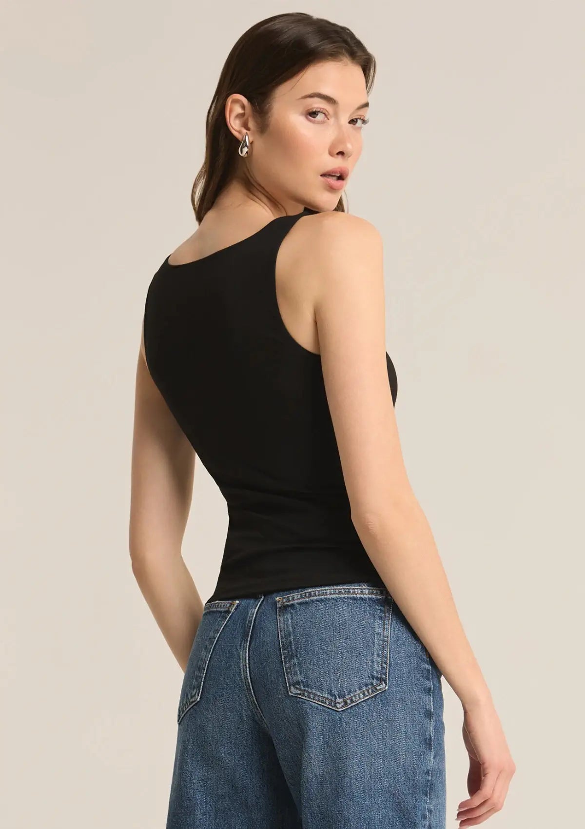 Black tank top paired with silver hoop earrings and blue jeans.