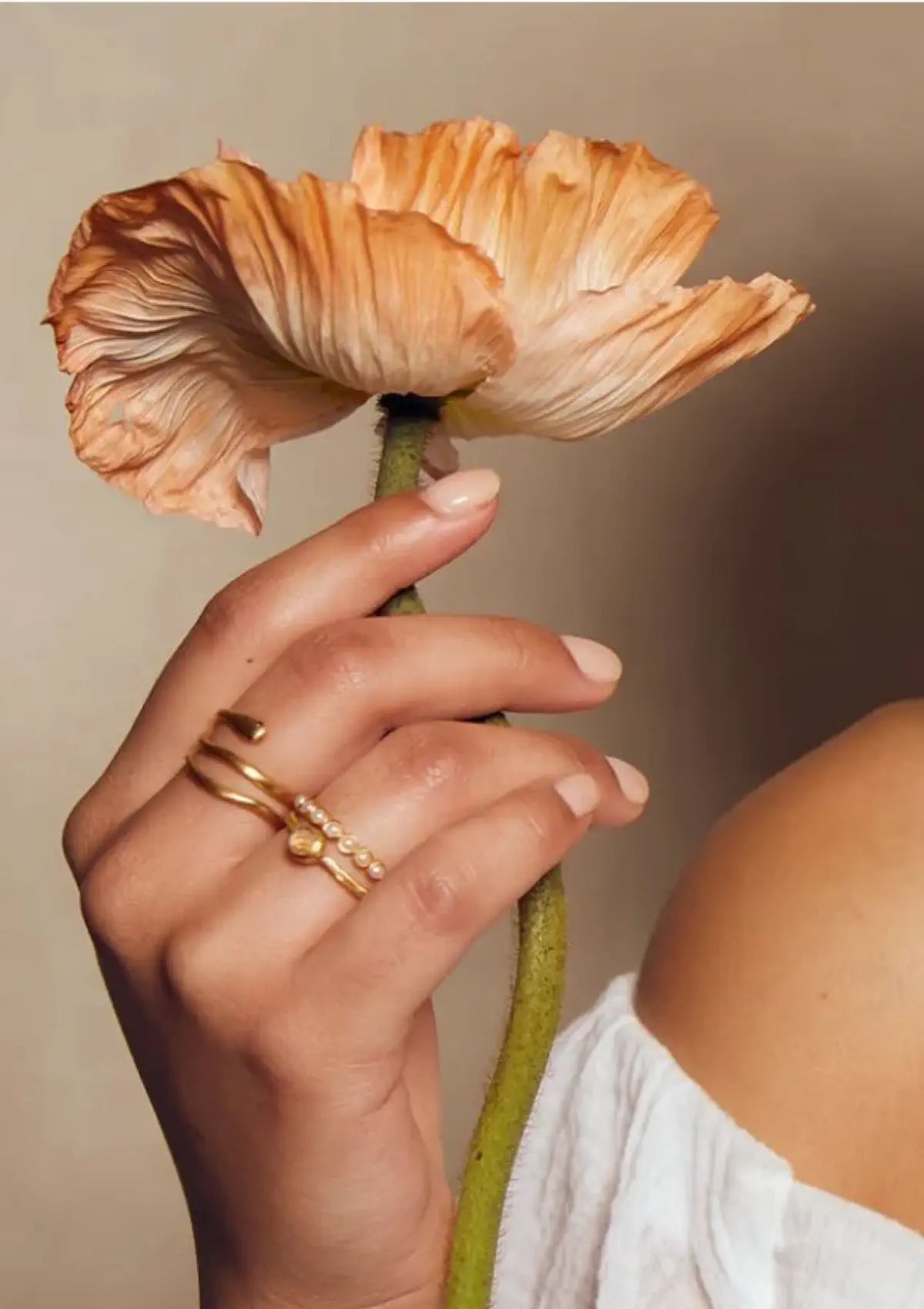 Paired with other gold rings, holding a flower.