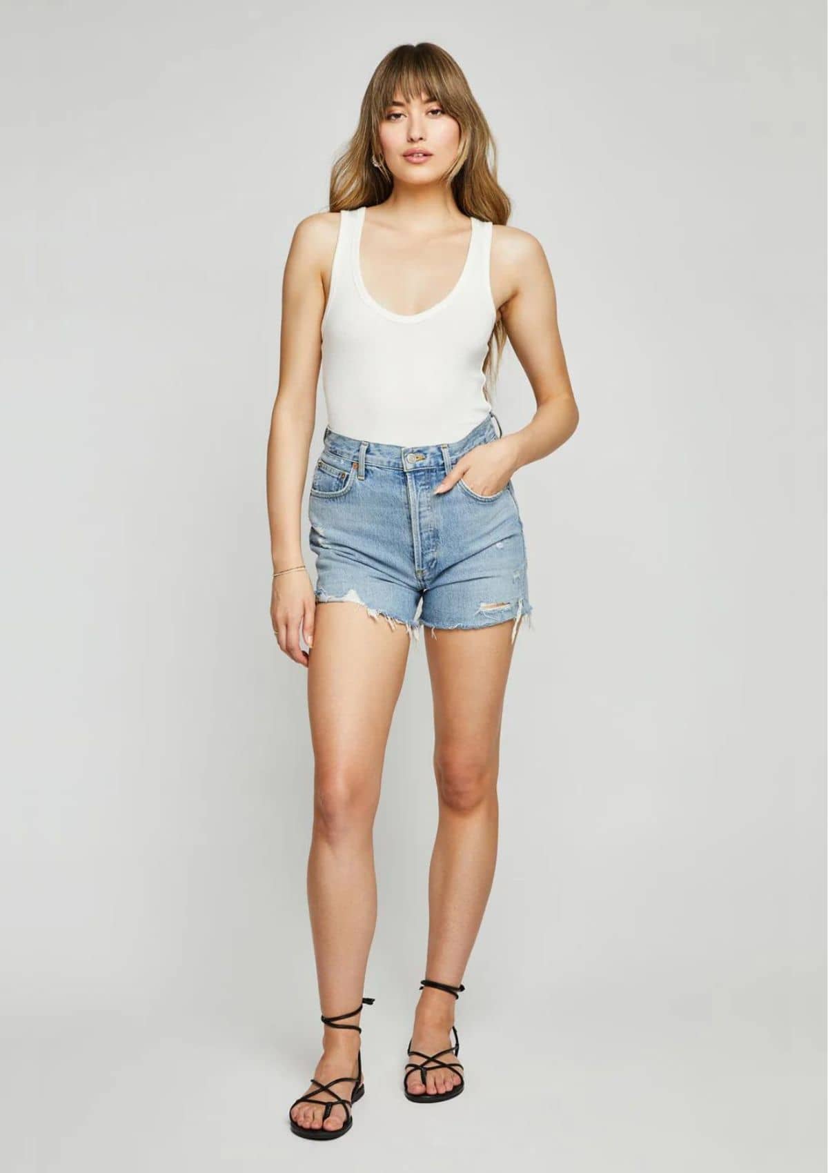 Deep scoop neck. Tucked in high rise blue jean shorts.