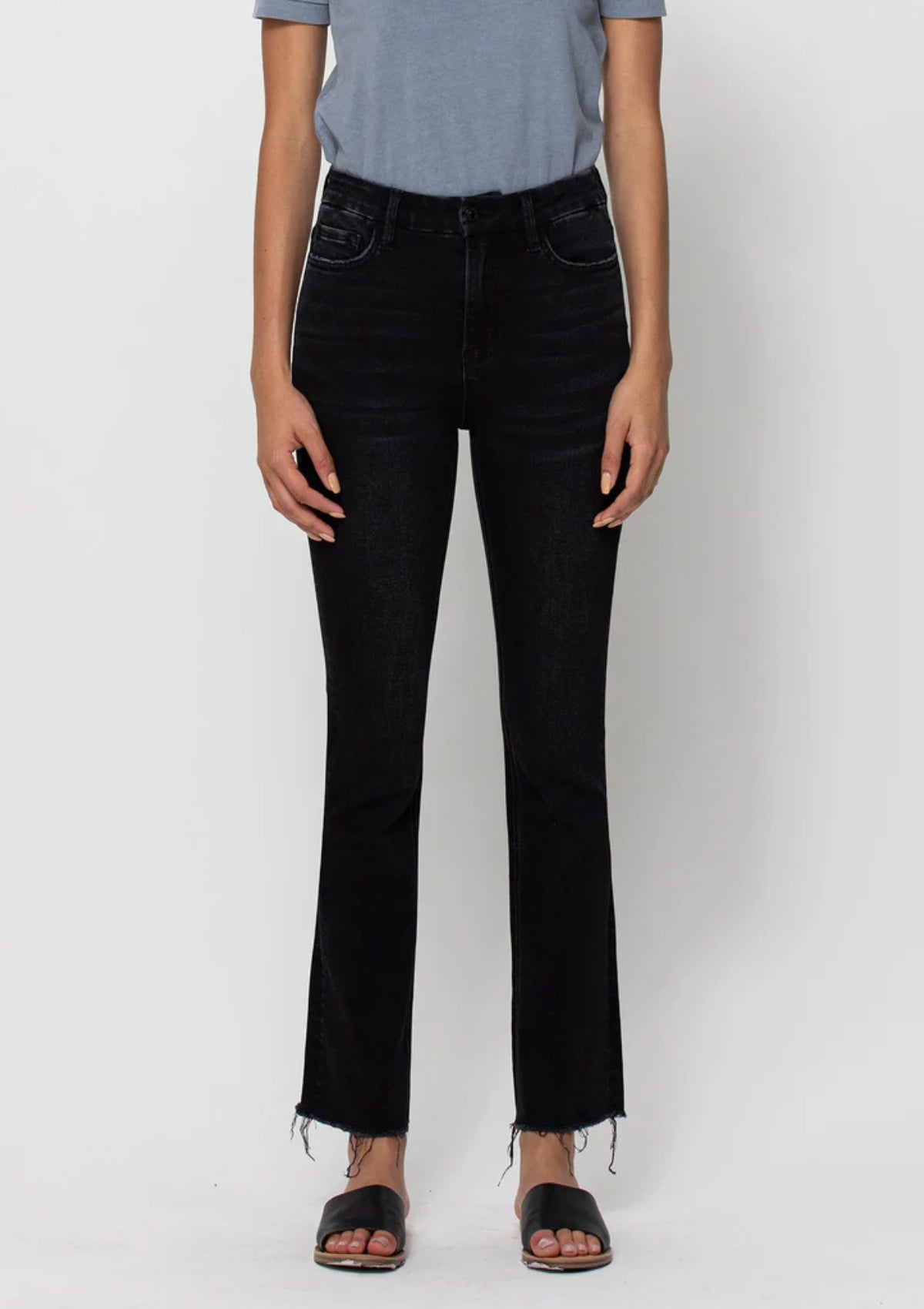 Black jeans with frayed ankle length hem.