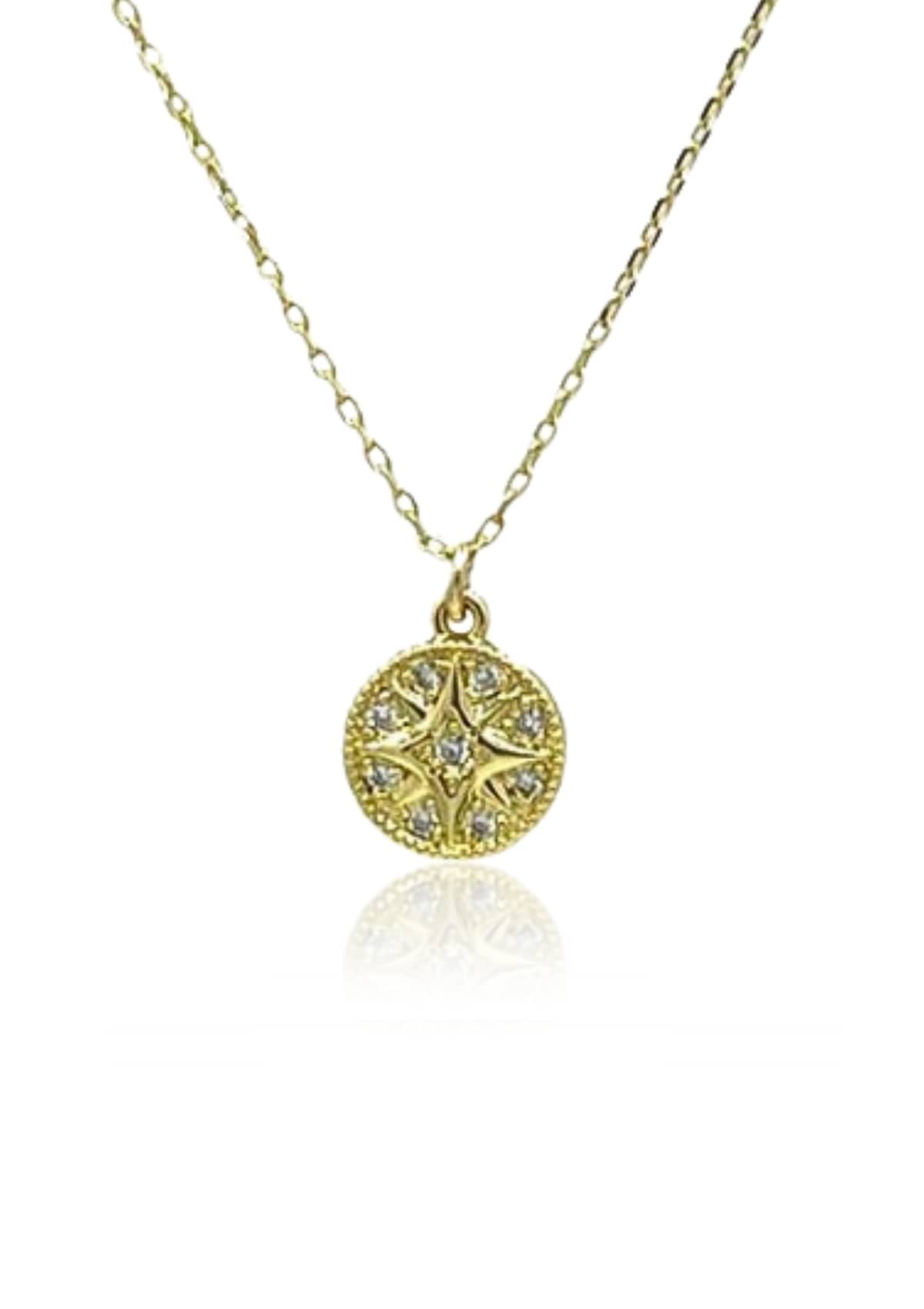 Gold chain necklace with round pendant with star in middle.